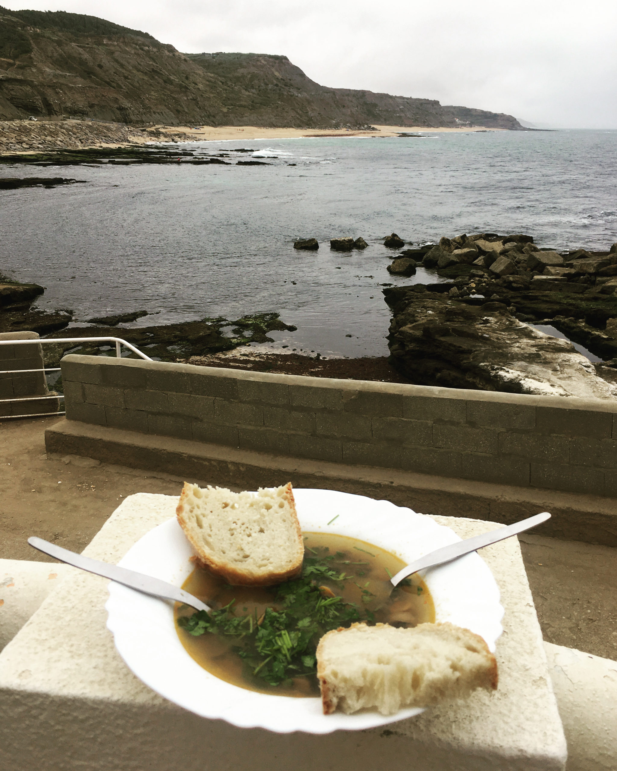 limpets soup in a bowl in front of a portuguese beach