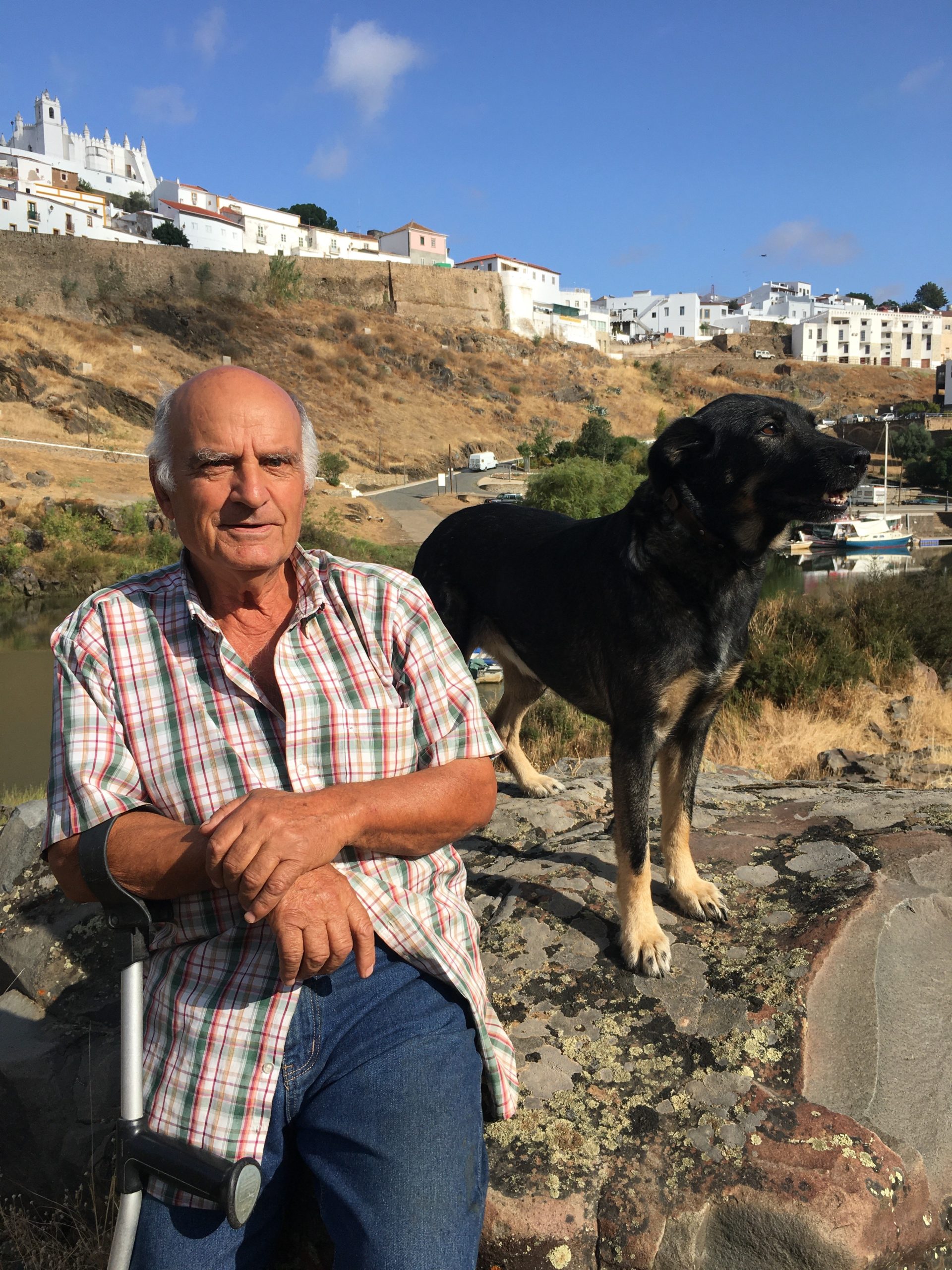 a man and a dog sitting on a rock