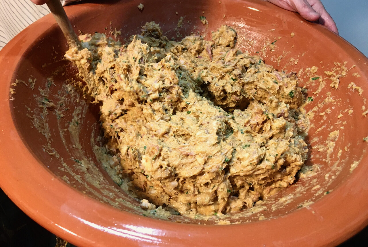 a clay pot where a woman is mixing ingredients do to a Portuguese sausage